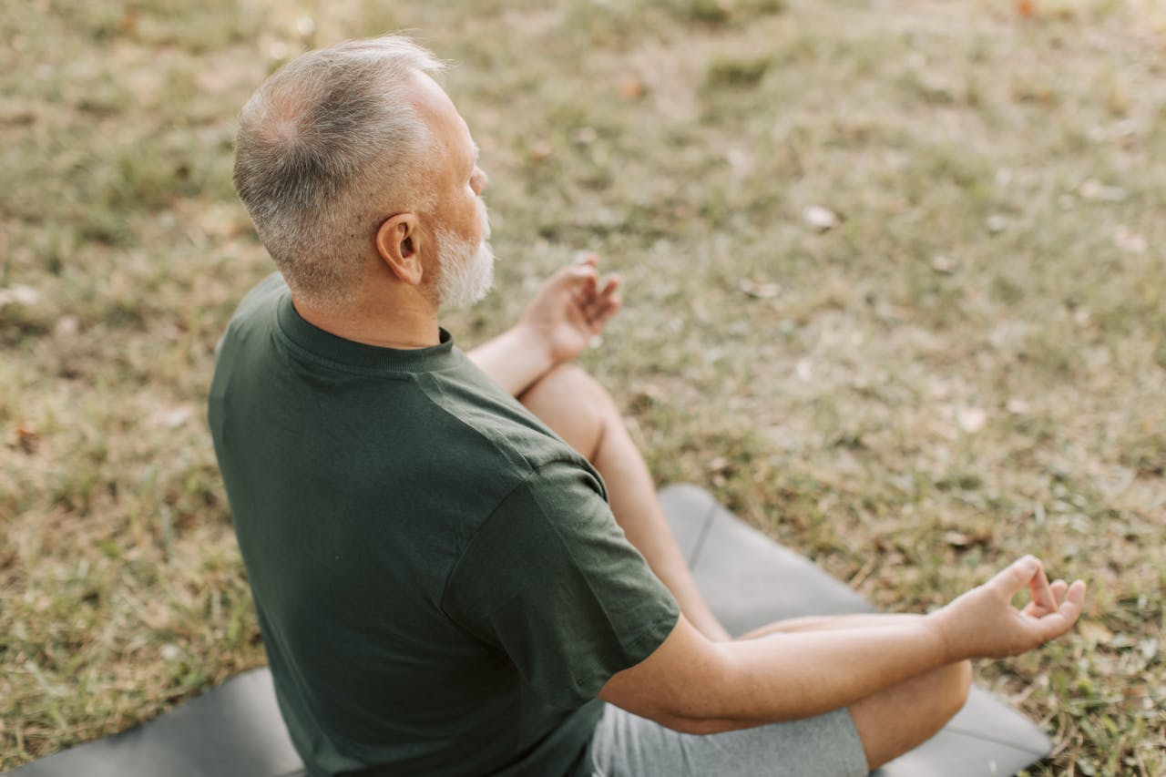 Senior man practicing yoga in a serene outdoor setting, promoting wellness and mindfulness.