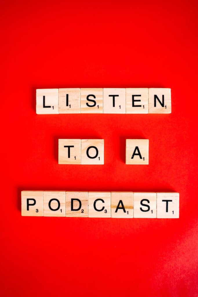 Wooden Scrabble tiles on red background spelling Listen to a Podcast.
